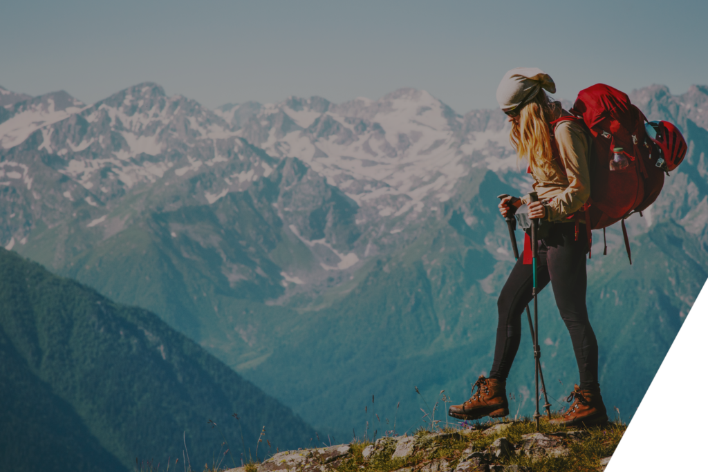 woman hiking at the top of a hill overlooking mountains
