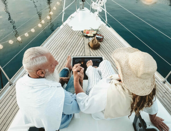 older retired couple holding hands on a boat