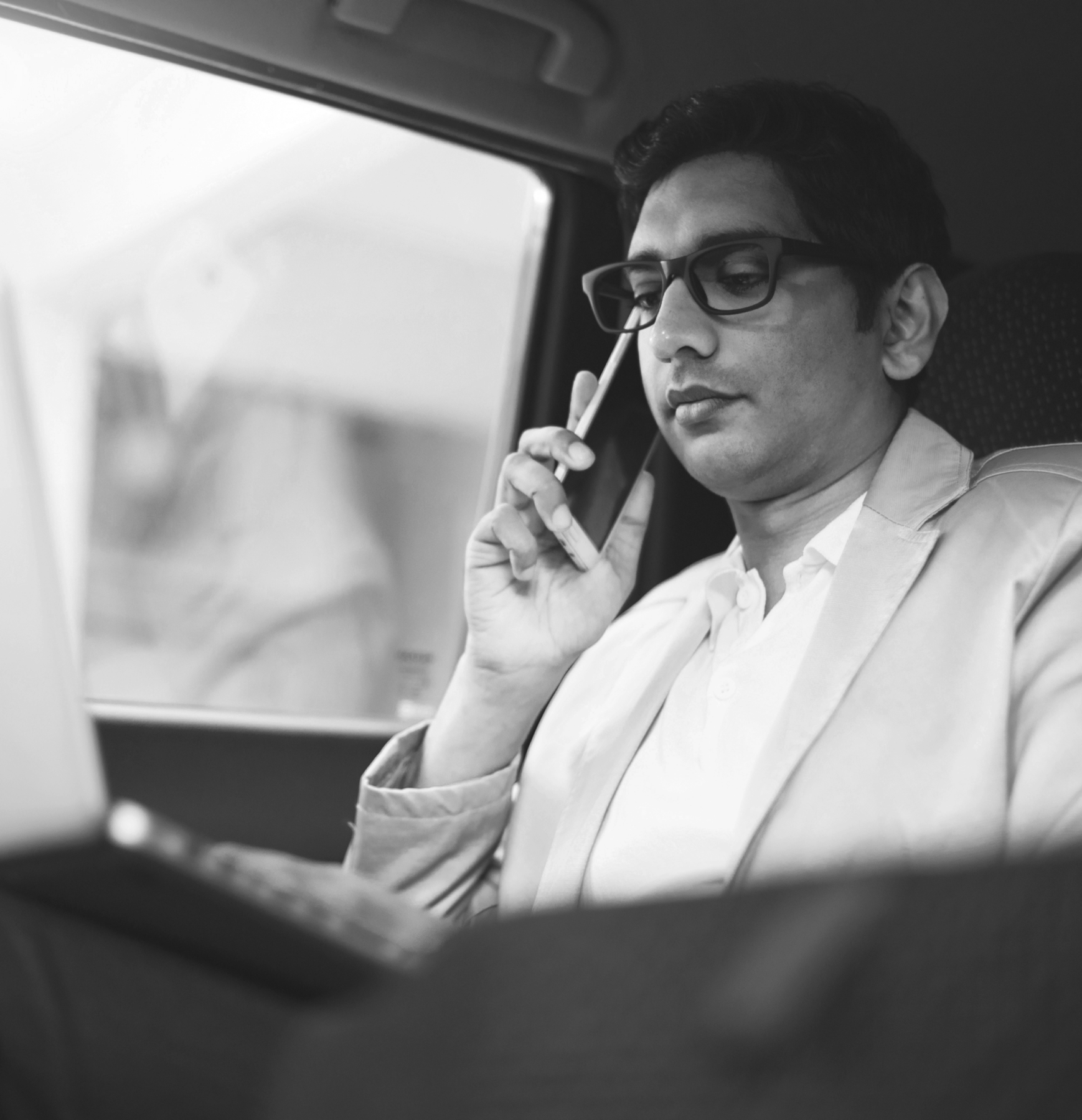 middle eastern young business man on the phone in backseat of a car